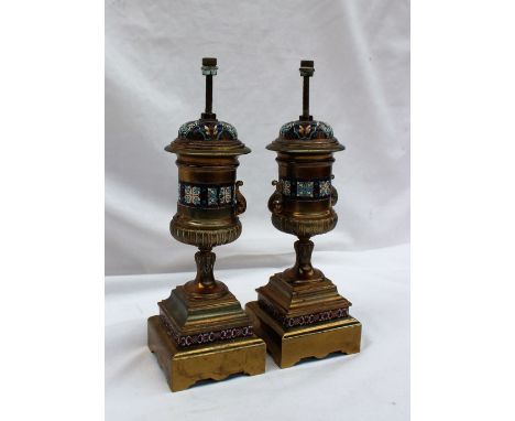 A pair of champleve enamel and gilt metal lamp bases, of twin handled urn shape, decorated with flower heads and leaves on sq