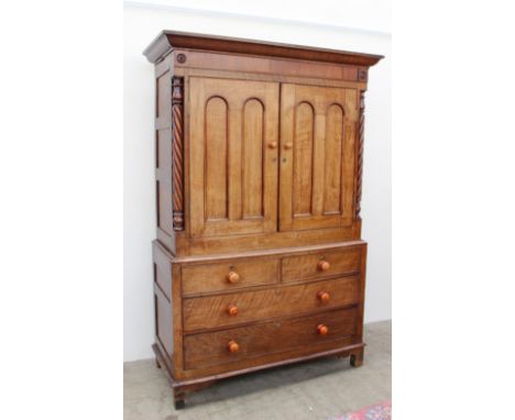 A Victorian oak linen press, the moulded cornice above a pair of panelled doors between rope twist columns, the base with two