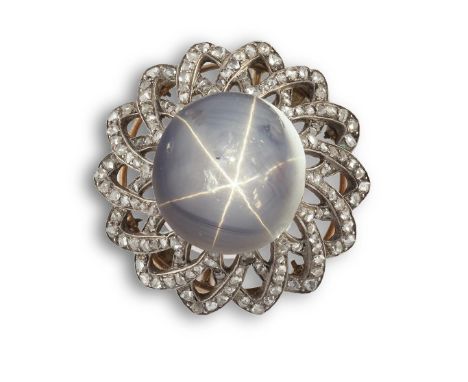 A STAR SAPPHIRE AND DIAMOND BROOCHThe oval cabochon star sapphire, within an overlapping openwork surround of rose-cut diamon