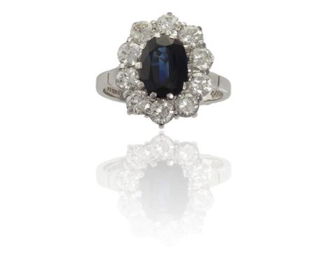 A SAPPHIRE AND DIAMOND RINGThe oval-cut sapphire, mounted in claw-setting, within a surround of round brilliant-cut diamonds,