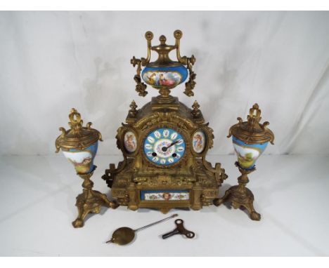 A late 19th century French clock garniture du cheminee, the spelter and gilded clock case in classical style accented by deco