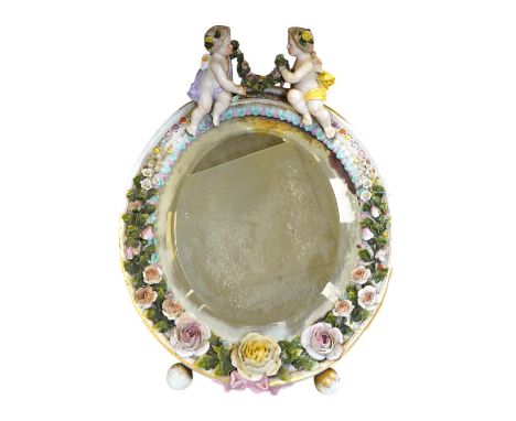 A Sitzendorf easel framed mirror, mounted with two putti holding a swag of roses, 35cm high. Condition - some damage to roses