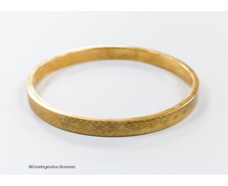   A 1920's engine turned 9ct gold bangle, interior diameter 76mm, 11.9 grams.