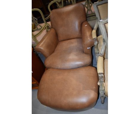 A modern armchair and pouffe having tan leather upholstery and turned feet