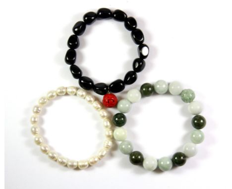 A pearl bracelet, a jade bead bracelet and a further stone bead bracelet.