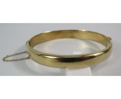9ct gold hinged bracelet bangle with safety chain, 10.9 grams.