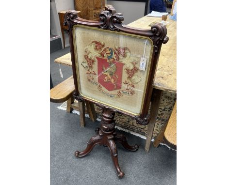 A Victorian carved mahogany firescreen, worked with armorial crest, width 64cm, height 119cmProvenance: Same owner since earl