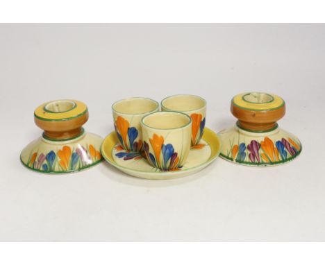 Clarice Cliff Crocus pattern items; a pair of candlesticks, 5cm high and three egg cups with stand One of the candlesticks wi