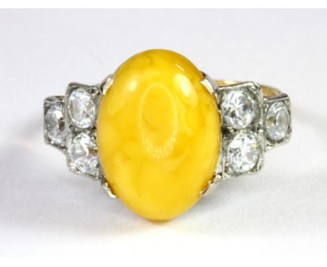 An 18ct yellow gold (stamped 18ct) ring set with a cabochon cut butterscotch amber and white stones (M).