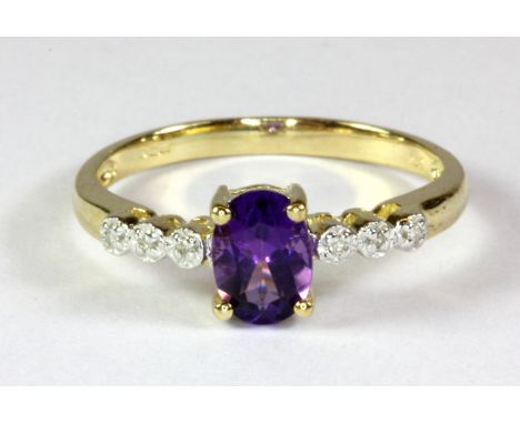 A 9ct yellow gold ring set with an oval cut amethyst and diamond set shoulders (P.5).