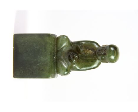 A mid 20th century Chinese green soapstone seal mounted with a young monk, H. 9.5cm.