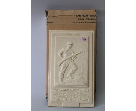 A WWII era cream Bakelite war Savings Campaign 1944 wall plaque with raised panel depicting advancing 'Tommy' with text below