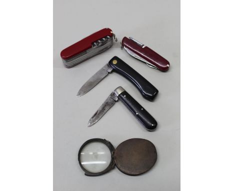 A multi-bladed/tools Victorinox Swiss knife with three other pocket knives and a 'glass'