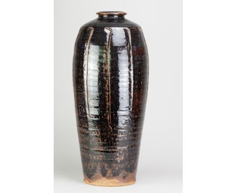 JIM MALONE (born 1946); a tall stoneware fluted bottle covered in tenmoku breaking to kaki glaze, impressed JM and A (for Ain