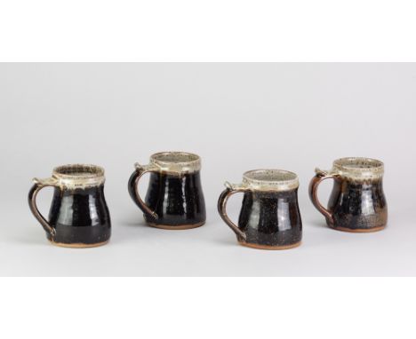 JIM MALONE (born 1946); a set of four stoneware mugs covered in tenmoku breaking to kaki glaze with green ash rims, impressed