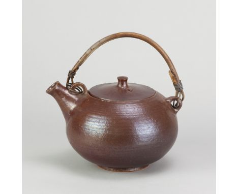 JOHN DAN (1930-1983) for Wivenhoe Pottery; a stoneware teapot with cane handle covered in iron rich glaze, incised JD and pot