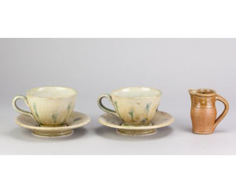 ANDREW YOUNG (born 1949) &amp; JOANNA YOUNG (born 1950); a pair of large stoneware cups and saucers covered in glossy green g