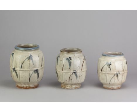 JIM MALONE (born 1946); a graduated trio of stoneware faceted jars covered in white slip with cobalt decoration, impressed JM