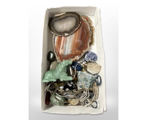 A group of agate geode slices, jade carving of a horse, various rough and polished semi-precious gemstones.