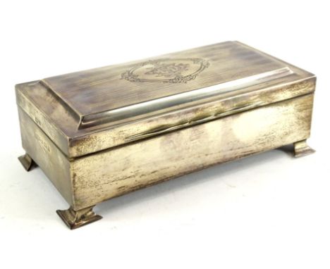 A George V silver cigarette box, the hinged shaped lid with engine turned decoration and with central monogram, within an ela