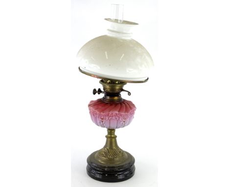 A Victorian brass oil lamp, with white opaque shade, pink tinted reservoir, on a ceramic base, 60cm high overall.