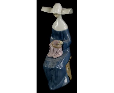 A Lladro porcelain figure of a seated nun doing embroidery, numbered to underside 5501, 20.5cm high (boxed).