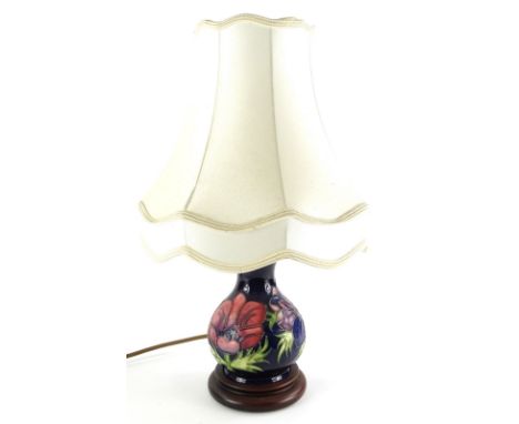 A Moorcroft pottery baluster shaped lamp base, decorated with poppies, on a navy blue ground, with composition base and cream
