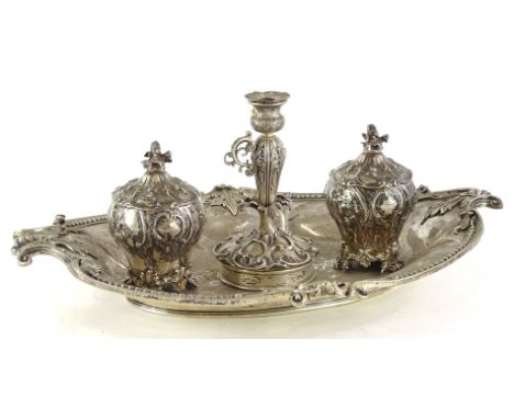 A Victorian silver inkstand, of oval form, with a shaped edge, engraved with a crest and with leaf cast borders, applied cent