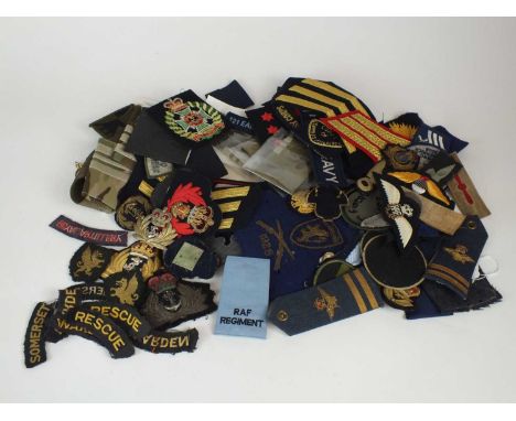 A mixed collection of predominantly post-war military cloth insignia, including shoulders chevrons, titles, patches badges - 