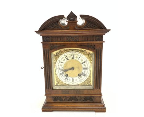 Late 19th century mantle clock in architectural walnut case, arched pediment with central leaf carved motif, enclosed by beve