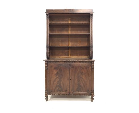 19th century mahogany bookcase on cupboard, three open shelves with beaded moulding, enclosed by scroll carved water leaves, 