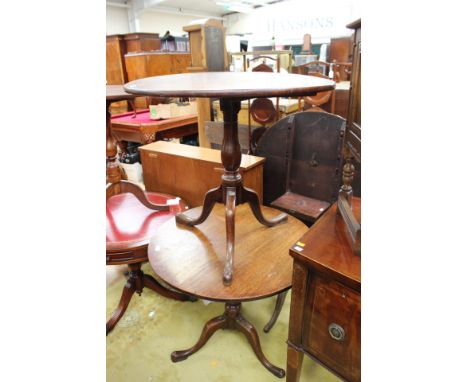 A pair of George III oak tripod tables, each with a circular tilting plank top, raised on a turned column and standing on thr