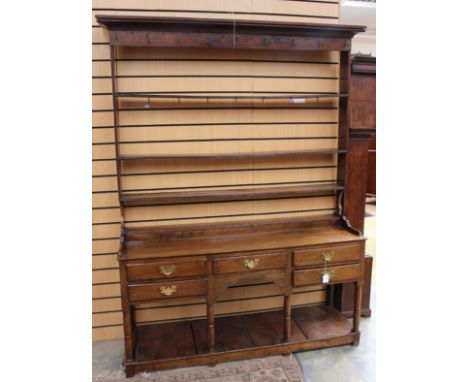 A George II oak dresser and rack, the rack with three plate shelves, the base having five drawers, raised on turned supports 