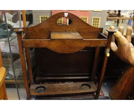 An early 20th Century oak stick stand, fitted with a hinged lidded section, two tin trays to base