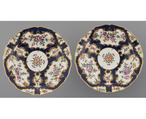 A PAIR OF WORCESTER SCALE BLUE GROUND SOUP PLATES, C1770&nbsp;painted with floral reserves in slightly upturned shaped gilt r