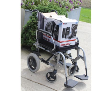 A wheelchair, together with a Trust 2.1 sub woofer computer speaker system
