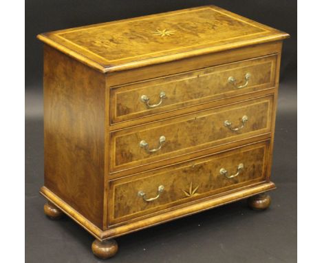 A walnut and inlaid chest of three drawers in the early 18th Century manner, the top with starburst inlay and applied moulded