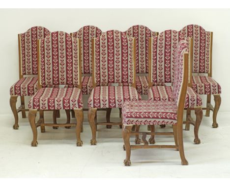 A set of eight dining chairs, carved walnut on cabriole legs united by stretchers, high arched backs, upholstered in hand emb