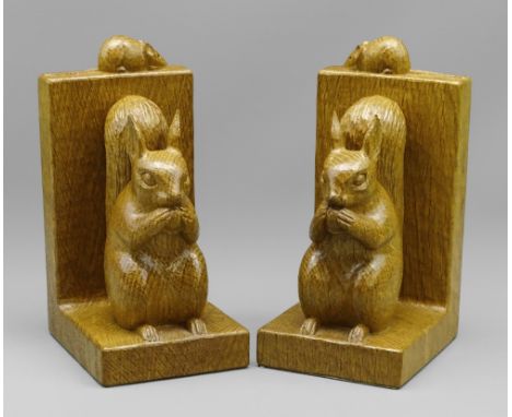 ROBERT 'MOUSEMAN' THOMPSON OF KILBURN: A PAIR OF CARVED OAK SQUIRREL BOOKENDS, each modelled with seated figure holding an ac