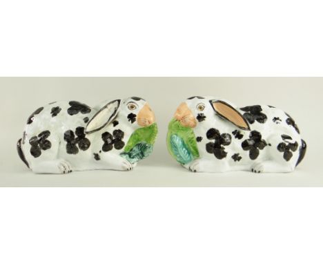 RARE PAIR OF VICTORIAN STAFFORDSHIRE POTTERY MODELS OF RABBITS, recumbent with lettuce leaves in their mouths, 24cms long (2)