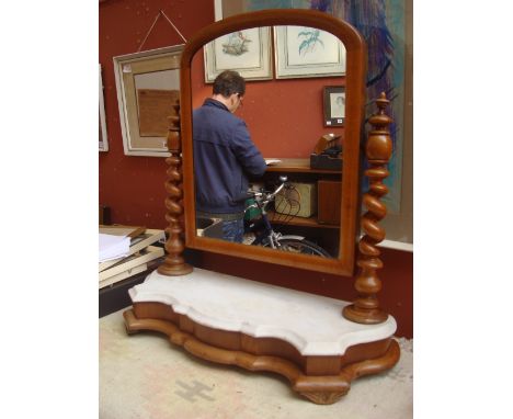 A late 19th Century pine framed toilet mirror, the arched top supported by barley twist columns, on a shaped marble shelf. 