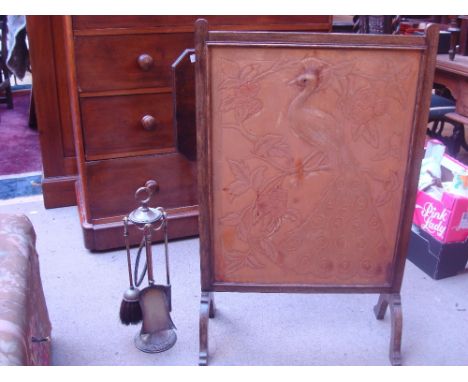 An Arts and Crafts oak firescreen, with leather panel embossed with a peacock among flowering branches together with an Edwar