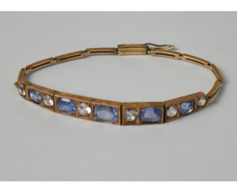 A pinkish yellow metal linear bracelet with cushion-cut violet-blue and round brilliant-cut white sapphires in bead and bezel