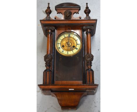 A 19th century mahogany-cased Vienna-style wall clock, central ornate classical design above enamel and gilded dial set with 