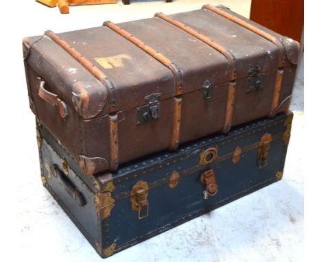 A large blue cabin trunk with brass furniture and leather handles and a further canvas trunk with leather handles and wooden 