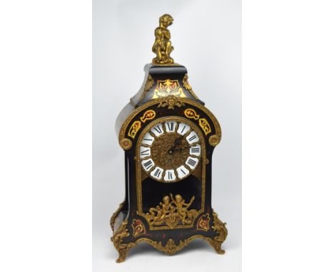 A reproduction Napoleon-style ebonised and gilded clock, ceramic and gilded dial set with Roman numerals, case with faux tort