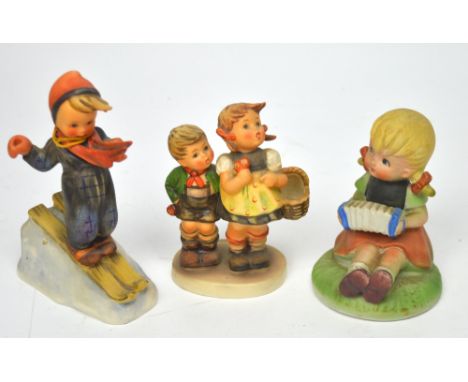Three Hummel figures to include a young boy on skis, little girl playing accordion and a young boy and girl with flowers and 