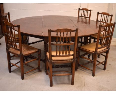 A c1900 oak oval drop-leaf dining table on turned and baluster supports and turned cross-stretchers and a set of six oak dini