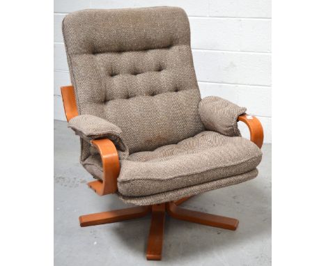 An early 1980s beech revolving easy chair with button-back brown and cream tweed upholstery.