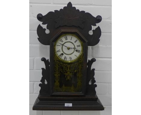 A Jerome wall clock with stained oak case and gilt glass panel enclosing an enamelled dial with Roman numerals and brass chap